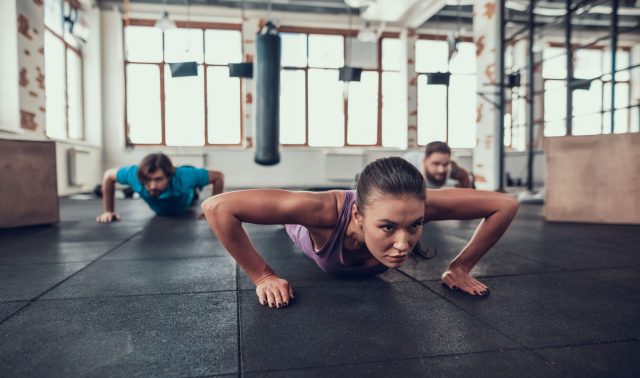 Men And Woman Doing Push Ups. Training Day. Fitness Club. Healthy Lifestyle. Powerful Athlete. Active Holidays. Crossfit Concept. Bright Gym. Comfortable Sportswear. Triceps Muscles.